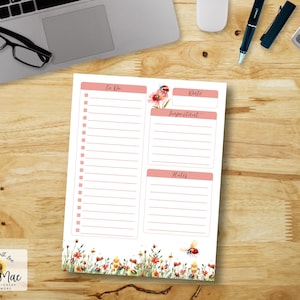 Puede incluir: Un bloc de notas con lista de tareas con temática floral con secciones para Hacer, Fecha, Importante y Notas. El bloc de notas presenta un diseño floral de acuarela con una mariquita y está colocado sobre un escritorio de madera con un portátil, gafas, bolígrafo y calculadora.