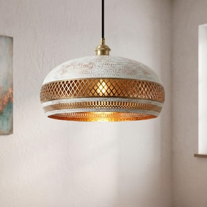 May include: A dome-shaped pendant light fixture featuring a distressed white finish on the exterior and a metallic gold interior. A central band displays a decorative diamond-shaped lattice pattern, suspended from a black cord with a brass-toned cap.