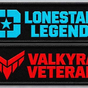 Puede incluir: Dos parches rectangulares bordados con bordes negros. El parche superior presenta un icono de estrella azul brillante y el texto LONESTAR LEGEND. El parche inferior muestra un emblema geométrico rojo en forma de ala y el texto VALKYRA VETERAN.