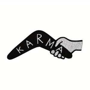 Pode incluir: Um emblema bordado em forma de bumerangue com fundo preto e costura branca. A palavra KARMA está bordada em letras maiúsculas brancas ao longo da curva, e uma mão branca é retratada agarrando a extremidade da forma de bumerangue.