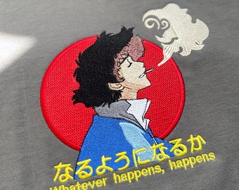 May include: Gray t-shirt with an embroidered design featuring a character with black hair, a blue jacket, and a red circle background. The design includes Japanese text and the English phrase "Whatever happens, happens."