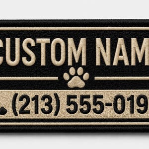 Könnte beinhalten: Ein rechteckiger bestickter Aufnäher mit schwarzem Hintergrund und beigem Rand. Der Text CUSTOM NAME steht in Beige über einem Pfotenabdruck-Symbol. Darunter befindet sich ein beiges Feld mit einem Telefon-Symbol und (213) 555-0198.