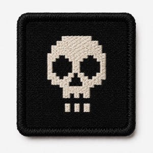 May include: A square embroidered patch with a black background and a beige pixelated skull design. The patch features a thick black stitched border around the edges, creating a clean frame for the central skull graphic composed of small squares.