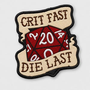 May include: An embroidered patch featuring a red twenty-sided die with white numbers, including a prominent 20. The die is centered between two beige banners with black borders. The top banner reads CRIT FAST and the bottom reads DIE LAST.