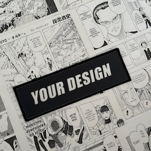 May include: A black rectangular patch with the text "YOUR DESIGN" in white, set against a backdrop of black and white manga comic pages. The comic pages feature various panels with Japanese text and illustrations.