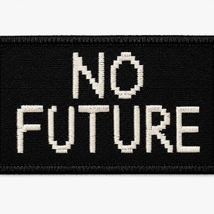 Pode incluir: Um emblema retangular bordado em preto com uma borda costurada. O texto NO FUTURE está centralizado em branco, apresentando um estilo de fonte pixelizado e em blocos. O bordado tem uma textura visível sobre o fundo de tecido preto.