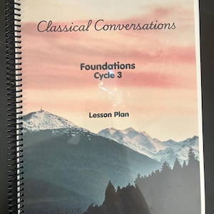 May include: A spiral-bound lesson plan book titled Classical Conversations Foundations Cycle 3. The cover features a landscape image of a snow-capped mountain range under a pink and orange sunset sky, with a dark forest in the foreground and Edition 1 2026.