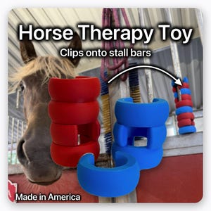 May include: A horse therapy toy consisting of stackable, C-shaped foam rings in bright red and blue. The text reads Horse Therapy Toy, Clips onto stall bars, and Made in America. The rings are designed to attach to vertical metal stall bars.