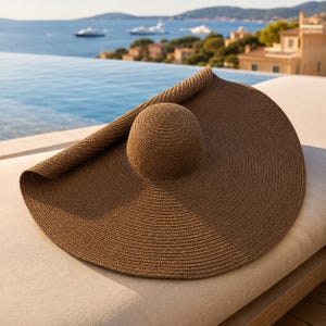 May include: A large, brown sun hat with a wide brim and a rounded crown. The hat is made of woven material and is resting on a beige surface. The hat's brim is partially rolled up, revealing the interior.