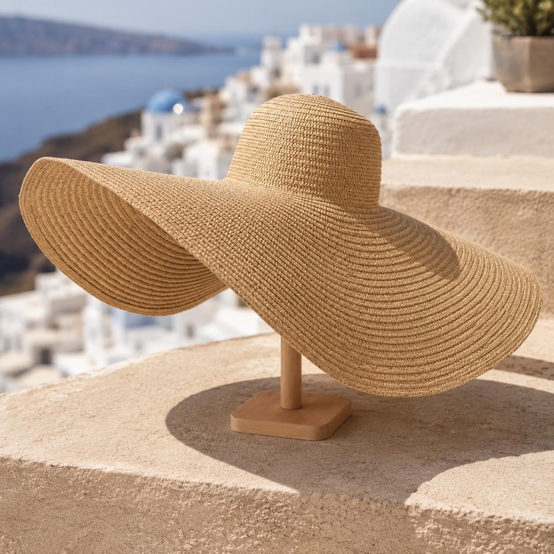 May include: A wide-brimmed, beige sun hat made of woven straw. The hat is displayed on a wooden stand, showcasing its large, circular brim and rounded crown. The hat's design suggests a focus on sun protection and style.