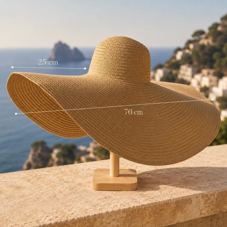 May include: A wide-brimmed sun hat made of woven straw, displayed on a wooden stand. The hat's brim measures 27.5 inches across, with a crown height of 9.8 inches. The hat is a light tan color, perfect for sun protection.
