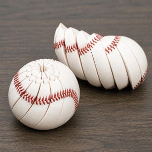May include: A set of white baseball-themed coasters that stack together to form a sphere. Each coaster is white with red stitching details, mimicking the appearance of a baseball. When stacked, the individual pieces align to create a round shape.