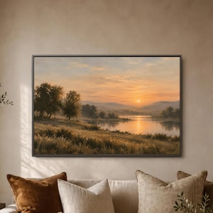 May include: A rectangular landscape painting in a dark frame depicting a sunset over a calm river. The scene features golden light reflecting on the water, rolling hills in the distance, and silhouettes of trees along the grassy riverbank.