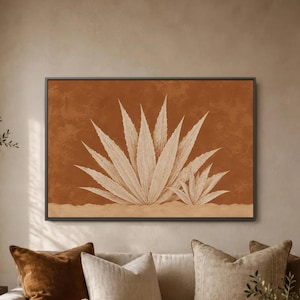 May include: A rectangular wall art piece featuring a horizontal orientation with a dark frame. The artwork displays a stylized illustration of two agave plants in a light beige tone set against a solid, textured, deep terracotta orange background.