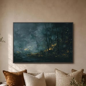 May include: Abstract art print in a dark teal and gold color palette. The artwork features a forest scene with light streaks and golden specks, framed in a dark wooden frame. The painting is displayed above a sofa with decorative pillows.