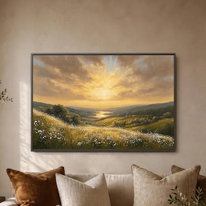 May include: A rectangular framed landscape painting depicting a golden sunset over a rolling valley. The foreground features a grassy meadow filled with small white wildflowers, leading to distant hills and a glowing horizon under clouds.