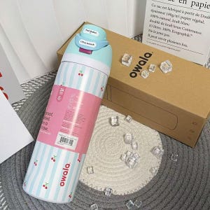 May include: A stainless steel Owala water bottle with a light blue and white striped pattern, adorned with cherry illustrations. The bottle features a pink band with product information and a blue lid with a push button and "Lift to Unlock" text.
