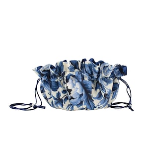 May include: A blue and white floral drawstring pouch with a ruffled top and blue drawstrings.