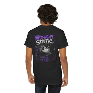 May include: Black t-shirt with the text "Midnight Static" in purple and white. The graphic features a person's face emerging from water, with a cityscape silhouette below. The design is centered on the back of the shirt.