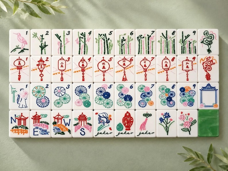 May include: A set of white Mahjong tiles arranged in four rows. The tiles feature colorful illustrations of bamboo stalks, lanterns, floral patterns, pagodas, and dragons. Some tiles include the letters N, E, W, S, and the word joker in script.
