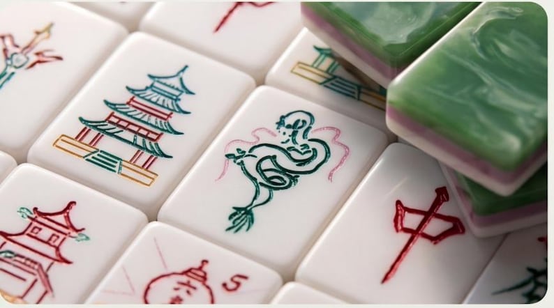 May include: A collection of white rectangular mahjong tiles featuring engraved and painted designs in red, green, and blue. The tiles display various symbols including a pagoda, a dragon, and Chinese characters, with some stacked green tiles.