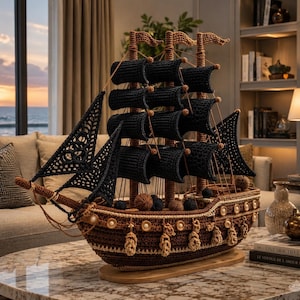 Pode incluir: Modelo de navio de crochê artesanal com velas pretas e casco marrom. O navio decorativo apresenta detalhes intrincados, incluindo borlas decorativas e pequenos detalhes em madeira. O navio está sobre uma base de madeira.