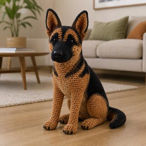 May include: A crocheted German Shepherd dog in a sitting position. The dog has a black and tan color scheme, with black markings on its back and head. The dog's ears are upright, and its tail is curled. The dog is sitting on a wooden floor.