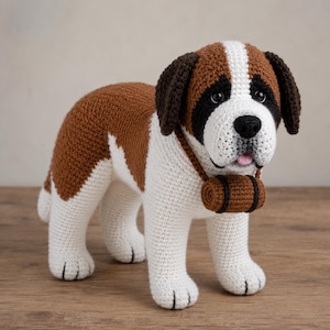 May include: A crocheted St. Bernard dog with brown and white markings, black eyes, and a pink tongue. The dog has a small brown pack slung over its shoulder. The handmade stuffed animal is standing on a wooden surface.
