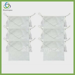 May include: Six white ceremonial aprons arranged in two vertical columns of three. Each apron features a triangular flap, a rectangular body, and white tassels attached to the sides with cords. The logo RiazImpex is visible in the top left corner.
