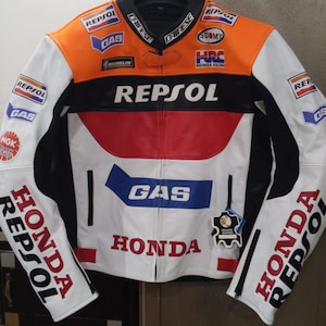 Könnte beinhalten: Eine mehrfarbige Motorradjacke mit weißen, orangefarbenen, roten und schwarzen Einsätzen. Die Jacke zeigt verschiedene Sponsorenlogos, darunter Repsol, Honda, Gas, Michelin, Suomy und NGK. Sie hat einen durchgehenden Frontreißverschluss und ein Lederetikett.