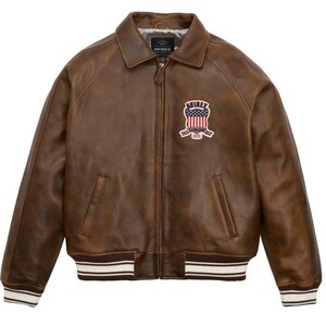 Puede incluir: Chaqueta de cuero marr&oacute;n con cremallera, cuello y pu&ntilde;os y dobladillo acanalados. Presenta un parche con un dise&ntilde;o de bandera americana y la marca "AVIREX". La chaqueta tiene dos bolsillos delanteros y un estilo bomber cl&aacute;sico.