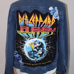 May include: A blue denim jacket featuring a large rectangular back patch with the text Def Leppard and Journey above a graphic of the Earth. The patch includes the text Summer Stadium Tour 2024 and is accented with embroidered blue floral appliqués.