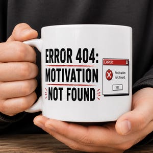 May include: White ceramic mug with the text "ERROR 404: MOTIVATION NOT FOUND" in black, with a red accent. A small graphic of an error message window is on the right side of the mug. The mug is held by a person.