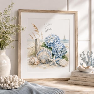 May include: A framed print featuring a coastal scene with blue hydrangeas, seashells, and a starfish on a sandy beach. The artwork includes the text "By the Sea" and is set in a light wood frame, evoking a serene, beachy theme.