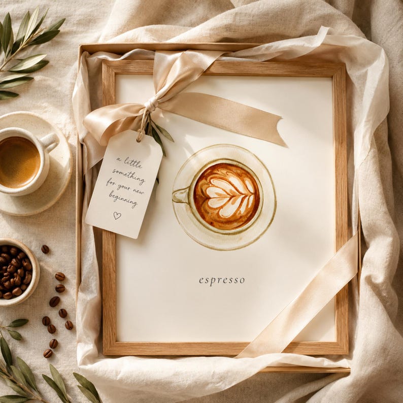 K&ouml;nnte beinhalten: Ein gerahmter Aquarelldruck eines Latte in einer Tasse mit Untertasse und dem Text 'espresso' darunter. Ein beiges Band ist um den Rahmen gebunden, an dem ein Schild mit der Aufschrift 'a little something for your new beginning' und einem kleinen Herzsymbol h&auml;ngt.