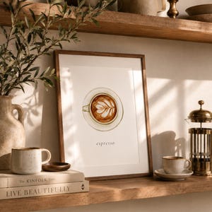 K&ouml;nnte beinhalten: Ein gerahmter Kunstdruck mit einer Aquarellillustration einer Kaffeetasse mit Latte-Art-Muster und dem darunter gedruckten Wort espresso. Das Kunstwerk ist in einem schlichten Holzrahmen pr&auml;sentiert und zeigt eine Draufsicht.