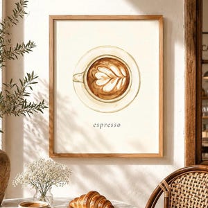 K&ouml;nnte beinhalten: Ein gerahmter Kunstdruck mit einer Aquarellillustration einer Kaffeetasse mit Latte-Art-Motiv in der Draufsicht. Der Hintergrund ist cremewei&szlig; und das Wort espresso ist in einer einfachen schwarzen Serifenschrift unter der Tasse gedruckt.
