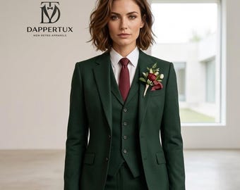 May include: A dark green three-piece suit featuring a blazer, a buttoned vest, and matching trousers. The suit is worn with a crisp white collared shirt and a solid burgundy necktie. A floral boutonniere with red and white flowers is pinned to the lapel.
