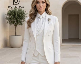 May include: A white three-piece suit consisting of a double-breasted blazer, a matching vest, and trousers. The blazer features a notched lapel, a white shirt, and a white tie. A silver floral brooch is pinned to the left lapel of the blazer.