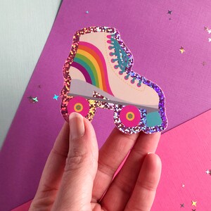 May include: A pink glitter roller skate sticker with a rainbow on the side. The wheels are red and yellow.