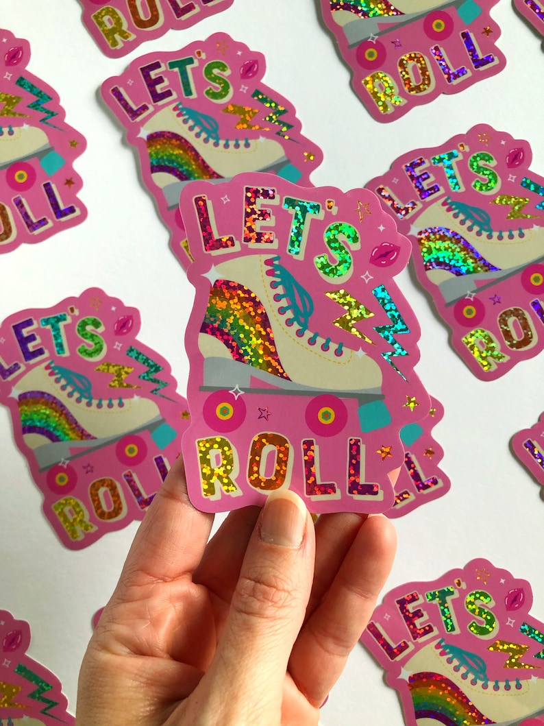 May include: Pink and white roller skate with rainbow glitter and the text "Let's Roll" in pink glitter.