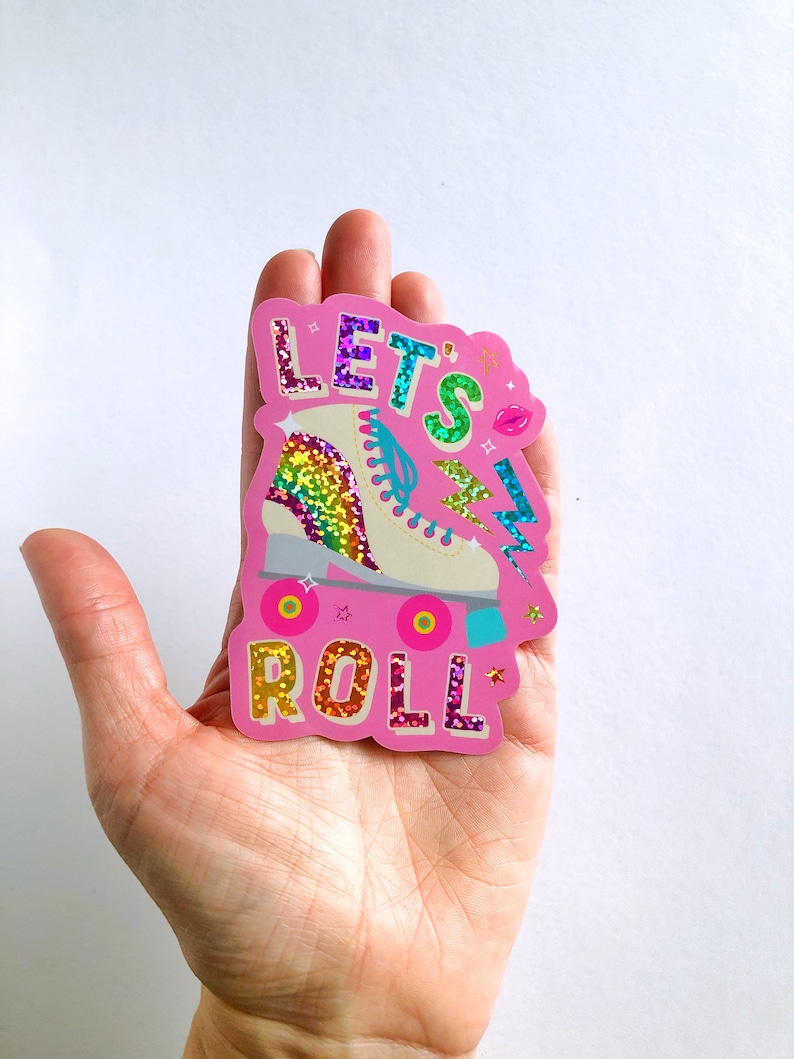 May include: Pink sticker with glitter text that says "Let's Roll" and a rainbow glitter roller skate with pink wheels.