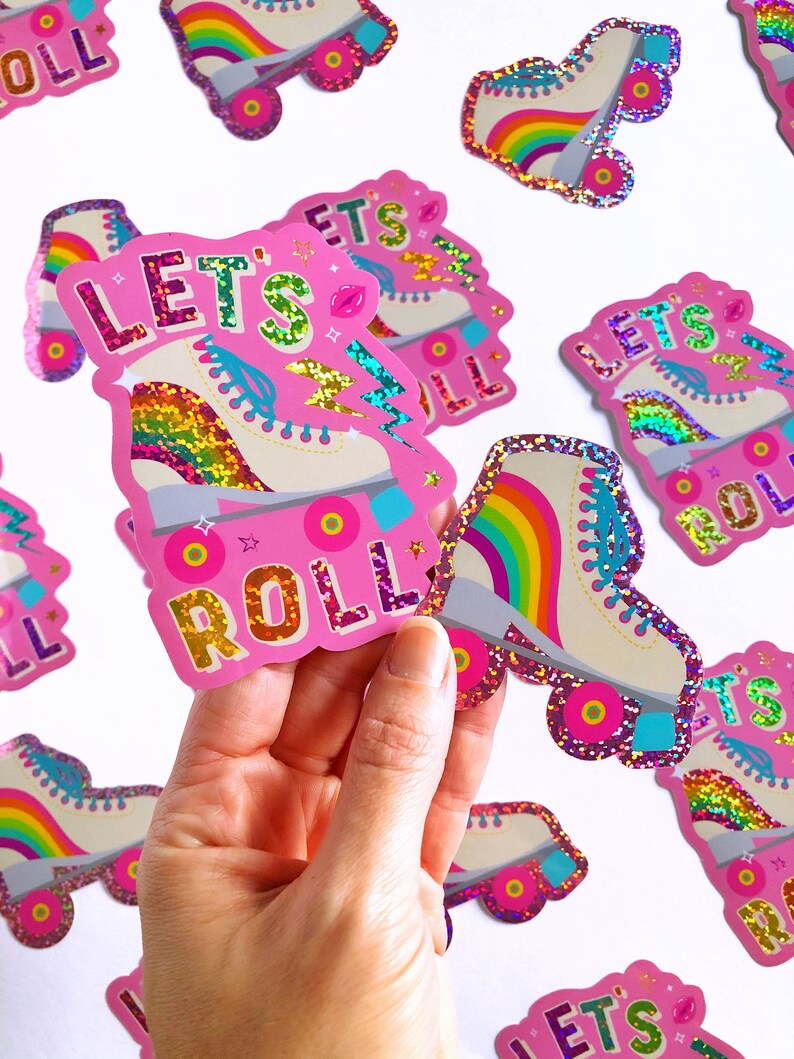 May include: A set of pink and white roller skate stickers with rainbow accents. The stickers feature the text "Let's Roll" and glitter accents.