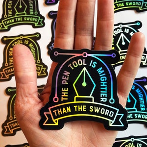 Puede incluir: Una pegatina negra e iridiscente con el texto "The Pen Tool is Mightier Than The Sword" en un degradado arco&iacute;ris. La pegatina presenta un icono de herramienta de pluma estilizado con un c&iacute;rculo alrededor.