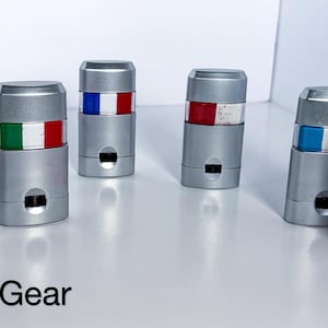 May include: Six silver-colored cylindrical objects with a black button and a colored band. The bands feature the colors of various national flags: green, yellow, and black; green, white, and red; blue, white, and red; red, white, and white; blue and white; and yellow, red, and black.