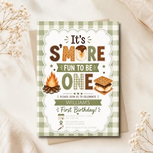 May include: A rectangular invitation card with a light green gingham border featuring the text It's S'MORE FUN TO BE ONE. The design includes illustrations of a campfire, a s'more, and event details for William's First Birthday on August 3, 2026.
