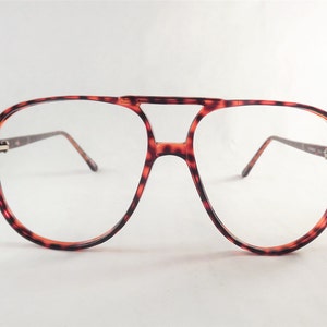 May include: Vintage aviator-style eyeglasses with a tortoiseshell pattern frame. The glasses have a double bridge and clear lenses. The temples are thin and dark, and the overall design is retro.