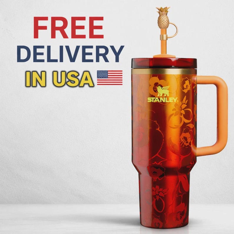 May include: A red and orange Stanley tumbler featuring a floral pattern, a matching orange handle, and a straw topped with a gold-colored pineapple charm. The text FREE DELIVERY IN USA with an American flag icon is visible to the left of the cup.