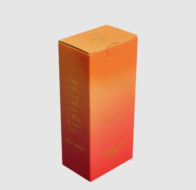 May include: A tall rectangular cardboard box with a vibrant orange to red gradient finish. The front and side panels feature printed text and a line drawing of a tumbler. The box displays product details and the text Tumbler 40 oz.