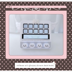 May include: A white stream deck featuring ten square buttons with character icons, a horizontal display screen, and four round knobs at the bottom decorated with white cartoon faces. The device includes a small white bow accent on the top edge.